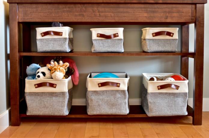A dark-brown wooden table contains six blue and white fabric storage bins separated by two shelves.