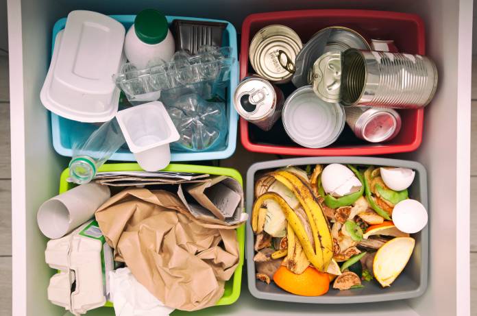 Close-up view of four different bins used to sort plastics, metal, compost, and paper for reuse and recycling.