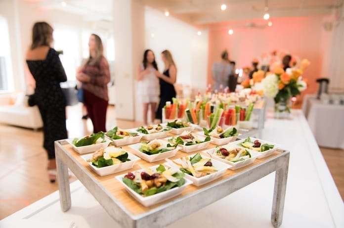 A close-up view shows an elegant display of side salads and vegetable cups for a fancy event. The background is blurry.