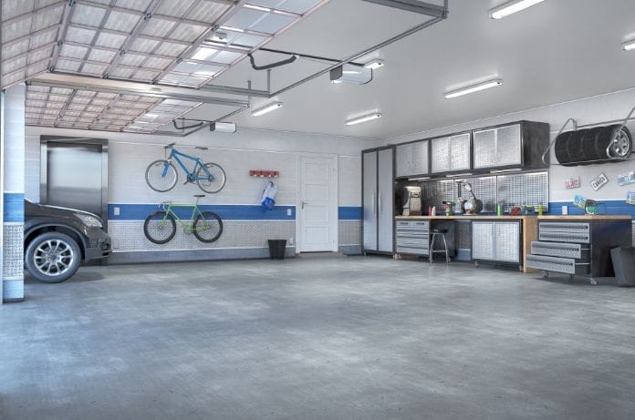A residential three-stall garage with concrete flooring, metal cabinets, mounted bikes, and a door leading into the home.
