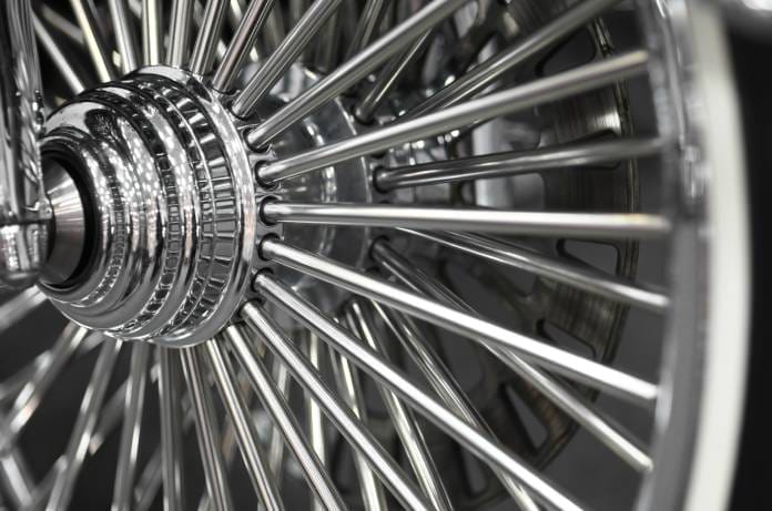 A close-up view shows a chrome spoke wheel that belongs to a motorcycle. The wheel is shiny and clean.