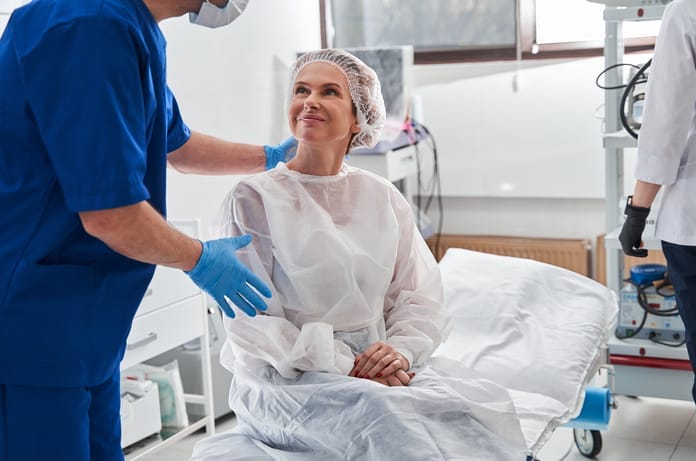 A male surgeon is talking to his patient and calming her down before her procedure, right before she goes under