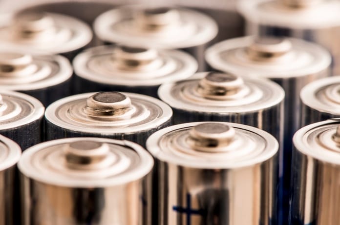An extreme close-up of multiple silver AAA batteries, showing only the top halves and the positive charge signs.