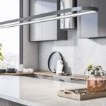 A kitchen in an apartment with a massive marble island. A window is open nearby, revealing the city skyline.