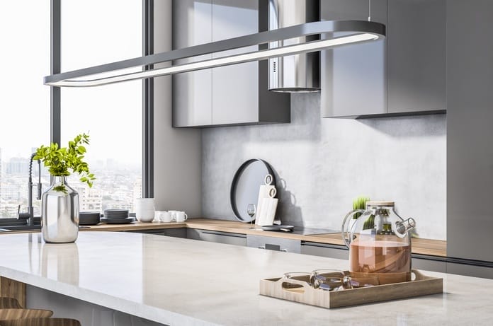 A kitchen in an apartment with a massive marble island. A window is open nearby, revealing the city skyline.