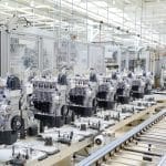 A large machine with multiple engines aligned, and a long metal conveyor belt with multiple thin rollers.