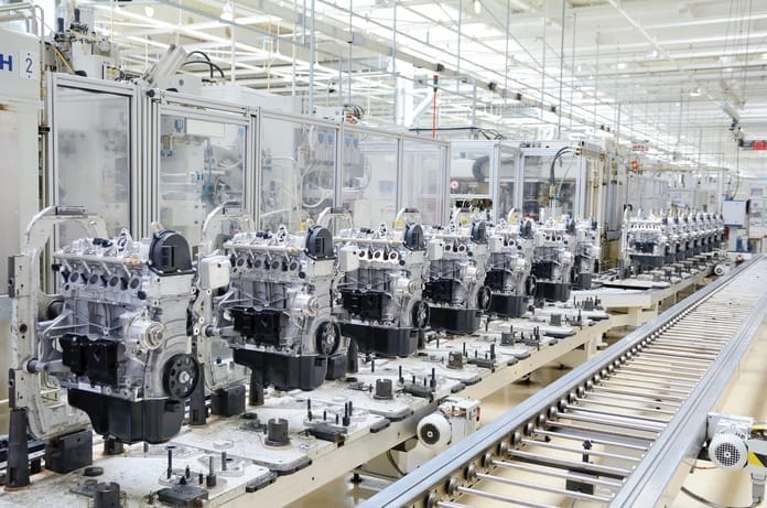 A large machine with multiple engines aligned, and a long metal conveyor belt with multiple thin rollers.