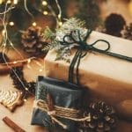 A close-up of a few Christmas presents wrapped in Kraft paper with black twine and a faux green garnish.